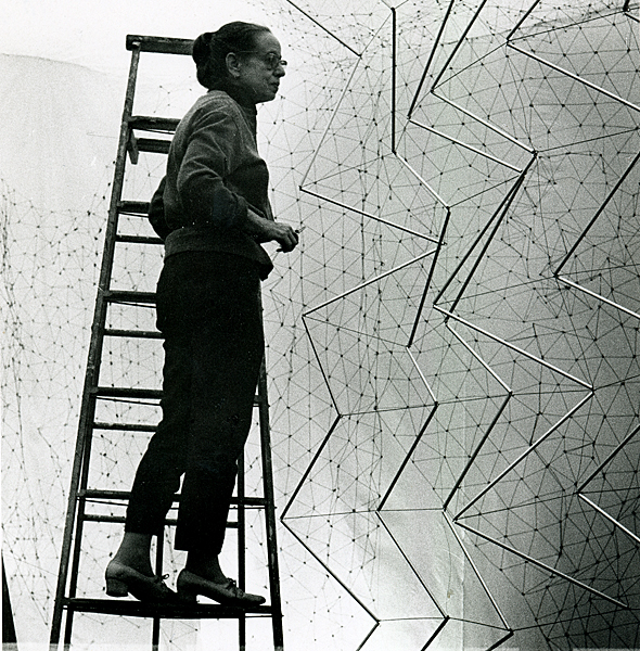 Gego working on “Reticularea (Ambientacion)” (stainless steel wire, netted, dimensions variable) at the Center for Interamerican Relations Art Gallery, New York, in 1969. Photo: Ana Mari?a Castillo. ©Fundacion? Gego. 